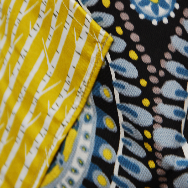 tablier à dos croisé aux beaux motifs bohèmes et poches en tissus à fond jaune.