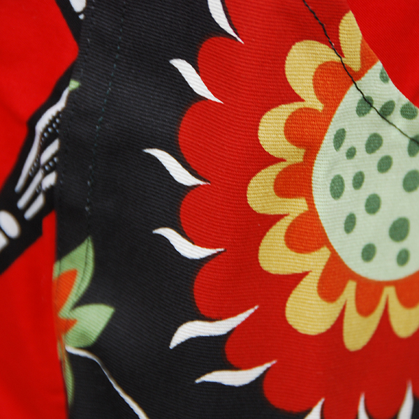 Tablier en très belle wax d'un beau rouge avec motifs 'ombrelles' en noir et blanc avec poches aux motifs floraux sur fond noir.