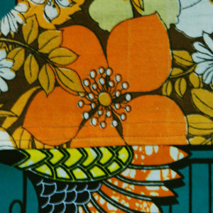 tablier en wax avec fond vert et grues stylisées avec des poches en tissu retro seventies